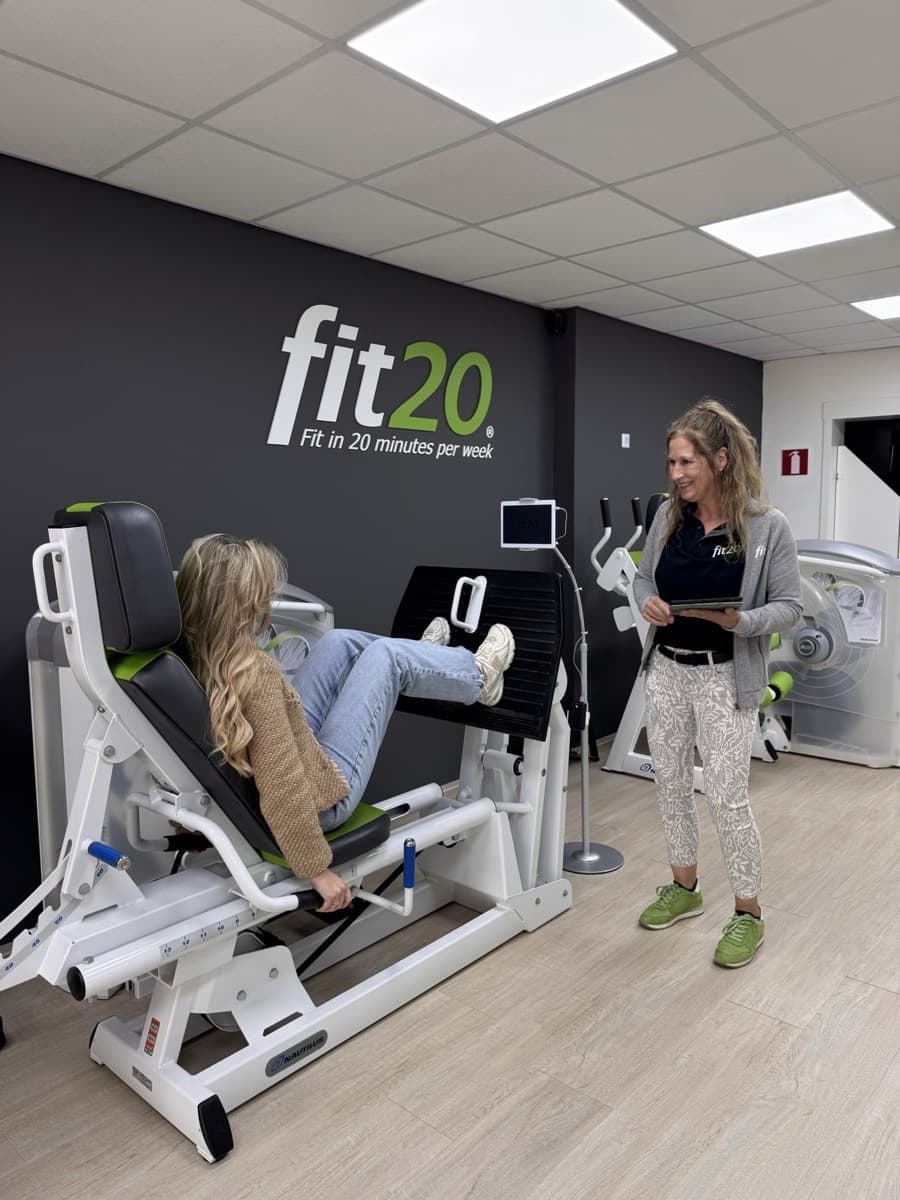 Trainer begeleidt een lid op de leg press in de fit20 studio Zevenaar